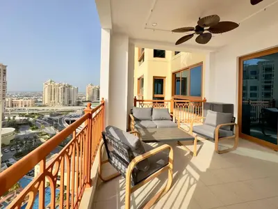 a balcony with two chairs and a ceiling fan at Luxury Spacious 2BR in Palm Jumeirah in Dubai