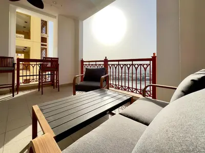 a living room with a couch and a chair on a balcony at Luxury Spacious 2BR in Palm Jumeirah in Dubai