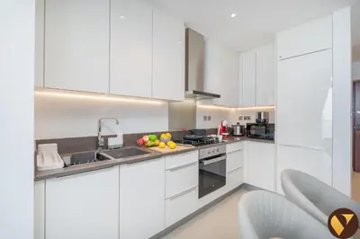 a kitchen with white cabinets and a bowl of fruit on the counter at Vogue Marina Gate near JBR Beach and Marina Mall, One Bedroom Apartment with Balcony and city skyline view, Access to all Amenities in Dubai