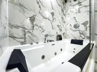 a white bath tub in a bathroom with marble walls at Luxury Stay - Private Jacuzzi - Infinity Pool - Marina & Sea Views - High Floor - Upgraded - Designer - Squash in Dubai