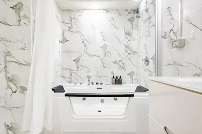 a white bathroom with a sink and a shower at Luxury Stay - Private Jacuzzi - Infinity Pool - Marina & Sea Views - High Floor - Upgraded - Designer - Squash in Dubai