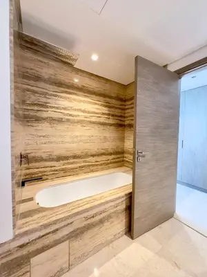 a bathtub in a bathroom with a wooden wall at Modern & Stylish 2BR Apartment in Dubai
