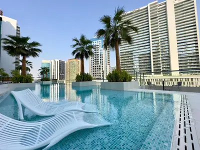 a swimming pool with palm trees and buildings at Modern & Stylish 2BR Apartment in Dubai