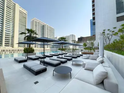 a rooftop patio with couches and tables and umbrellas at Modern & Stylish 2BR Apartment in Dubai