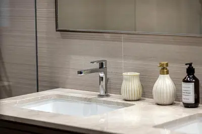 a bathroom sink with two vases and a mirror at 2BR Burj & Fountain View 5 mins to Dubai Mall in Dubai