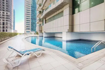 a hotel swimming pool with a chair and a building at Walk to Metro, Tram & Beach, Stylish 1BR in Marina Pinnacle, Dubai Marina by Deluxe Holiday Homes in Dubai