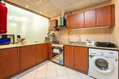 a kitchen with wooden cabinets and a washing machine at Walk to Metro, Tram & Beach, Stylish 1BR in Marina Pinnacle, Dubai Marina by Deluxe Holiday Homes in Dubai