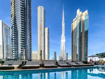 a swimming pool with chaise lounge chairs in a city at Vogue Downtown Act One near Burj Khalifa and Dubai Mall, Two Bedroom Apartment with Balcony and City Skyline View, Access to All Amenities in Dubai