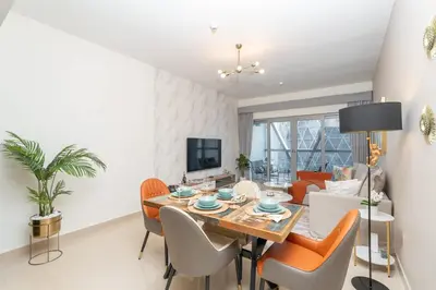 a dining room and living room with a table and chairs at StayShort - Stylish DIFC Apartment Sleeps 4 with Pool & Gym in Dubai
