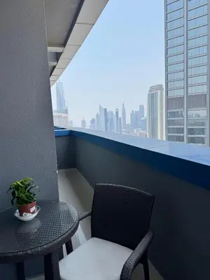 a table and a chair on a balcony with a window at Damac Maison Mall Street,Burj Khalifa in Dubai