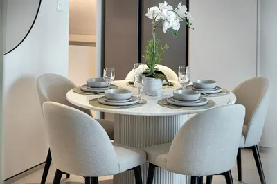 a dining room table with chairs and a round table with a centerpiece at Address JBR, 57th Floor Luxury Marina Beach View in Dubai