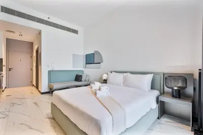 a bedroom with a large white bed and a couch at PVH - Serene Studio minutes to Downtown - MAG Eye in Dubai