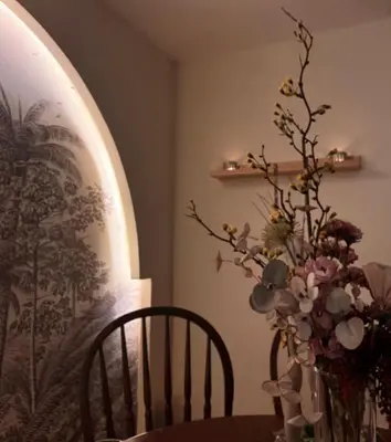 a table with a vase of flowers and a chair at Palm Oasis Guest House in Dubai