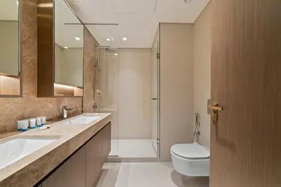 a bathroom with two sinks and a toilet and a shower at Werova - Luxury 2-Bedroom Apartment with Sea View in Dubai