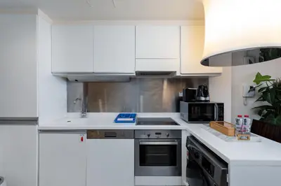 a white kitchen with a sink and a microwave at Panoramic Burj Khalifa Views - Modern & Comfy Gem in Dubai