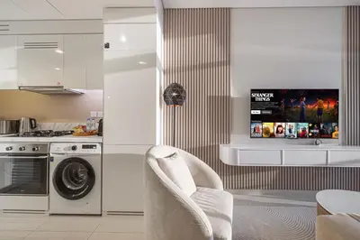 a kitchen with a washing machine and a tv at Cozy Sunset Retreat - Burj, Palm & Sea View - 2 BR in Dubai