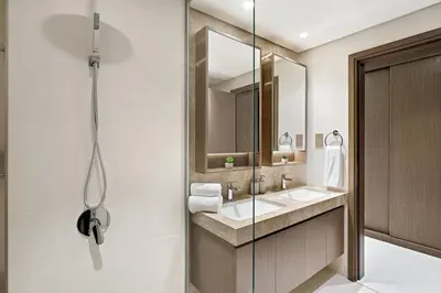 a bathroom with a shower and two sinks and a mirror at Elegant 2BR in Beachfront with Stunning Marina Views in Dubai