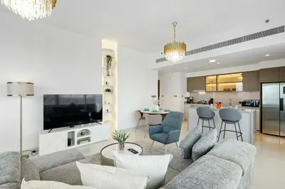 a living room with a couch and chairs and a kitchen at Elegant 2BR in Beachfront with Stunning Marina Views in Dubai