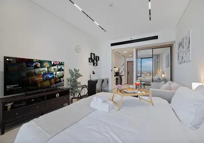 a living room with a large bed and a tv at Livin' Holidays - Studio - Canal view with jacuzzi in Dubai