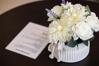 a white vase filled with white flowers on a table at Livin' Holidays - Studio - Canal view with jacuzzi in Dubai