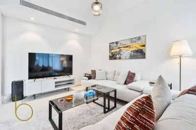 a living room with a white couch and a tv at Bookable - 4 Bedroom Elan 1 Tilal Al Ghaf Villa in Dubai