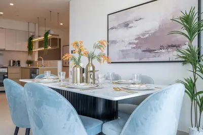 a dining room with a table and blue chairs at Luxury 3BR, MaidRoom Full Burj & Fountain Views in Dubai