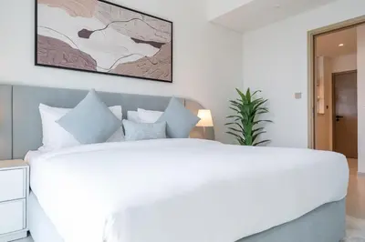 a bedroom with a large white bed with blue pillows at Luxury 3BR, MaidRoom Full Burj & Fountain Views in Dubai