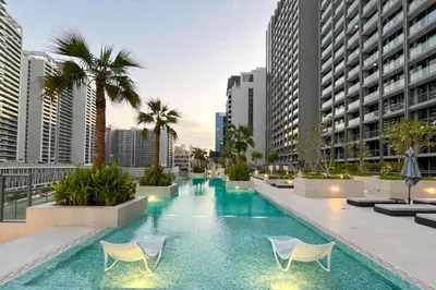 a pool with chairs and palm trees in a city at Modern Studio Near Dubai Mall Walk to Dubai Canal in Dubai