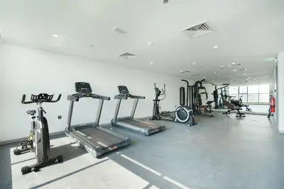 a gym with several tread machines in a room at Modern Home in Sports City with Rooftop Pool in Dubai