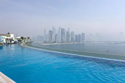 a large swimming pool with a city in the background at Stylish One-Bedroom Oasis - Prime Palm Location in Dubai