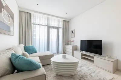 a white living room with a couch and a tv at Stylish One-Bedroom Oasis - Prime Palm Location in Dubai