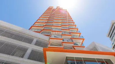 a tall building with orange and white at Pool View 1BR with Spacious Balcony, Short Drive to Downtown, Binghatti Gateway, Al Jaddaf by Deluxe Holiday Homes in Dubai