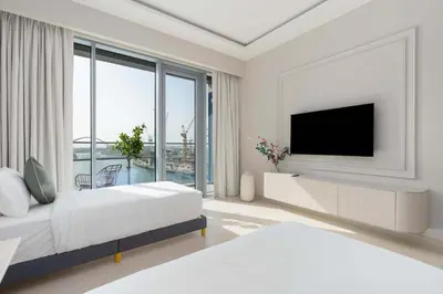 a white bedroom with two beds and a flat screen tv at Luxury 2BR and Study Water View in Al Wasl in Dubai