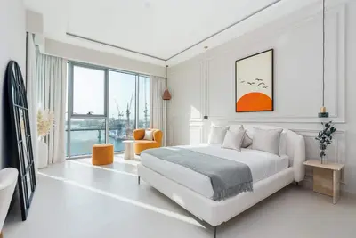 a white bedroom with a bed and a large window at Luxury 2BR and Study Water View in Al Wasl in Dubai