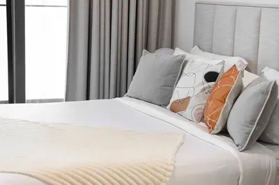 a white bed with pillows on top of it at Luxury 2BR with Canal View Burj Khalifa view and Infinity Pool Access in Dubai