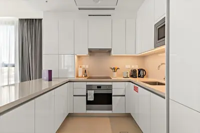a white kitchen with white cabinets and a sink at Silkhaus Elite 1BDR in Canal Front Tower in Dubai