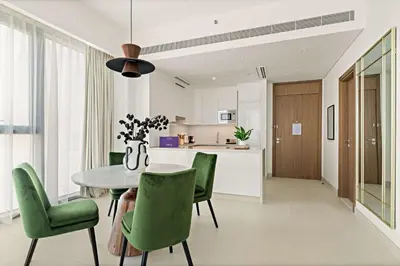 a kitchen and dining room with a table and green chairs at Silkhaus Luxury 1BDR Stay in Canal Front, Al Wasl in Dubai