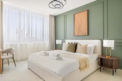 a bedroom with a large white bed with green walls at Silkhaus Cityscape 1BR in Sky Gardens with Metro access in Dubai