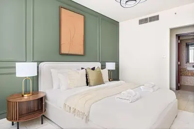 a bedroom with a white bed and green walls at Silkhaus Cityscape 1BR in Sky Gardens with Metro access in Dubai