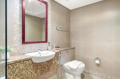 a bathroom with a sink and a toilet and a mirror at Silkhaus Cityscape 1BR in Sky Gardens with Metro access in Dubai