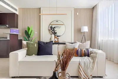 a living room with a white couch with colorful pillows at Silkhaus Cityscape 1BR in Sky Gardens with Metro access in Dubai