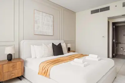 a white bedroom with a large bed and a wooden cabinet at Silkhaus Elegant 1BDR in Sky gardens with Metro Access in Dubai