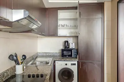 a kitchen with a washing machine and a sink at Silkhaus Exclusive 1BDR Stay at Sky Gardens in DIFC in Dubai
