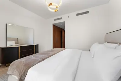 a white bedroom with a bed and a mirror at 3BR Central Park, Prime Dubai Location in Dubai