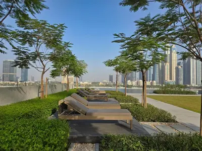 a row of benches in a park with a city skyline at Brand New 1BR , Fully Furnished in Dubai