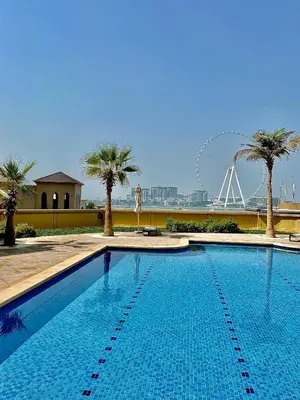 a swimming pool with palm trees and a ferris wheel at Fav 2-Bedroom by The Beach in JBR Bahar with stunning Marina View in Dubai