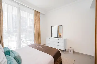 a white bedroom with a bed and a mirror at Escape24 Luxury 1BR with Sea View and Beach Access, Dubai Harbour in Dubai