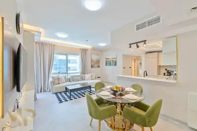 a living room with a table and green chairs at Marcopolo -Enjoy Marina views from a cozy 1BR in Dubai Marina in Dubai