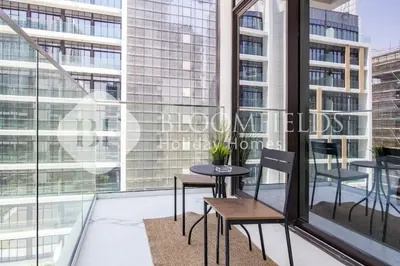 a balcony with a table and chairs and windows at Bloomfields Deluxe Studio In Azizi Riviera in Dubai