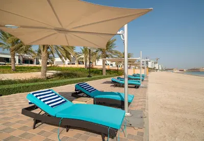 a row of lounge chairs with an umbrella on the beach at Luxury Beachfront Villa with Private Pool on Palm Jumeirah near Atlantis in Dubai